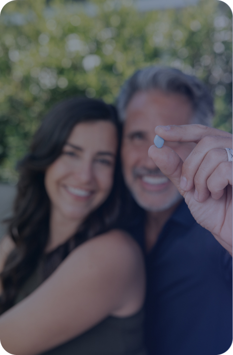 A couple is smiling in bed with Rex MD Viagra medication in front of them on a night stand
